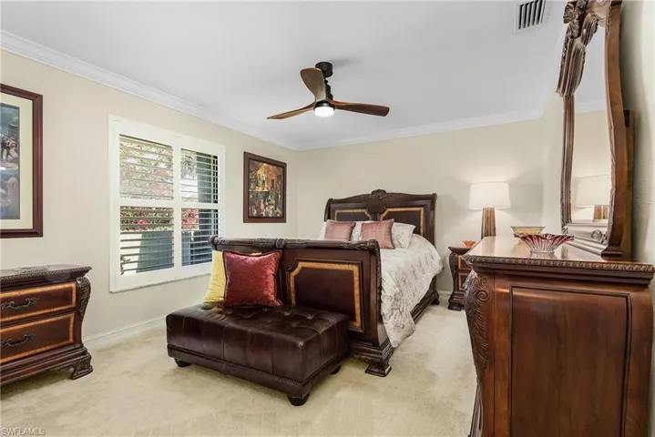 Carpeted guest bedroom featuring ceiling fan and crown molding