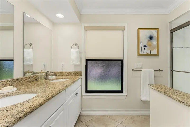 Master Bathroom featuring tile patterned floors, crown molding, a shower with door, and vanity