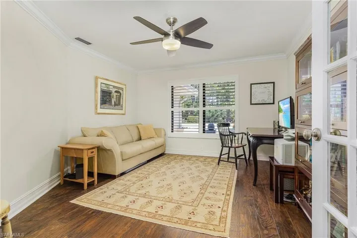 Den, ceiling fan, and dark wood-type flooring