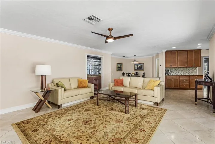 Tiled living room featuring ceiling fan and ornamental molding