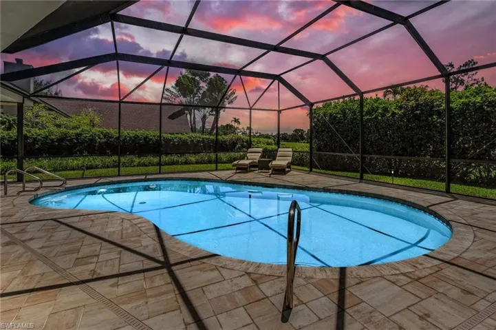 Pool at dusk with a lanai and a patio area