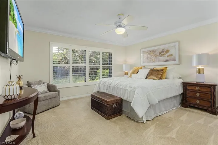 Guest Bedroom with ceiling fan, light carpet, and crown molding