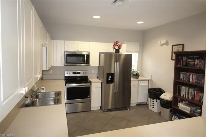 Kitchen with appliances with stainless steel finishes, white cabinetry, sink, and tile flooring
