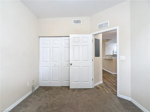 Unfurnished bedroom featuring a closet and dark carpet