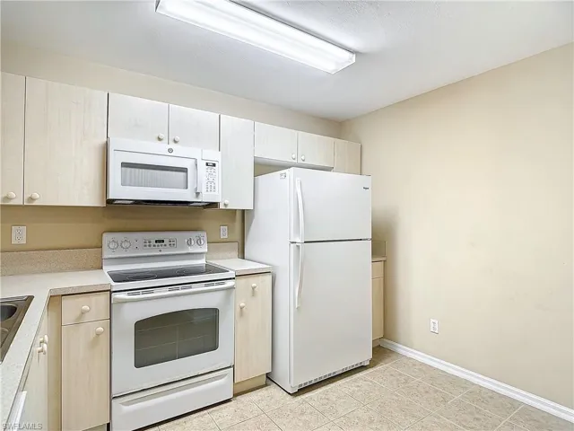 Kitchen featuring white appliances and light tile floors