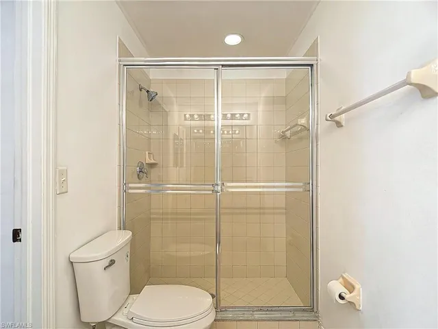 Bathroom featuring an enclosed shower, ornamental molding, and toilet