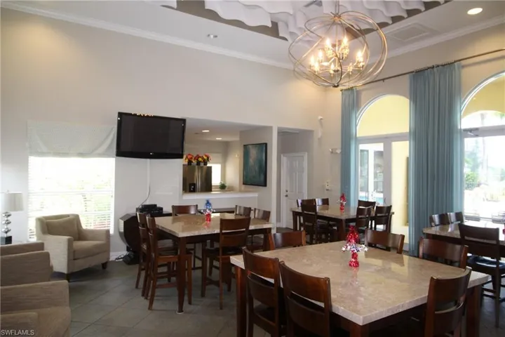 Dining area with dark tile flooring, a healthy amount of sunlight, crown molding, and a chandelier
