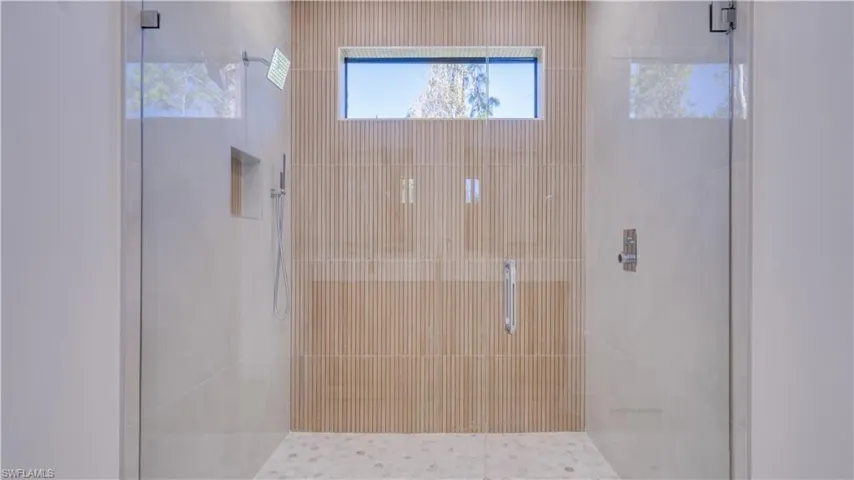 Primary walk-in shower with modern tile and multiple shower heads.