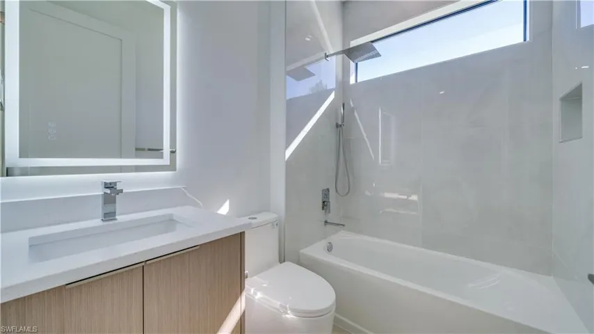 Guest bathroom with backlit mirror and multiple shower heads.