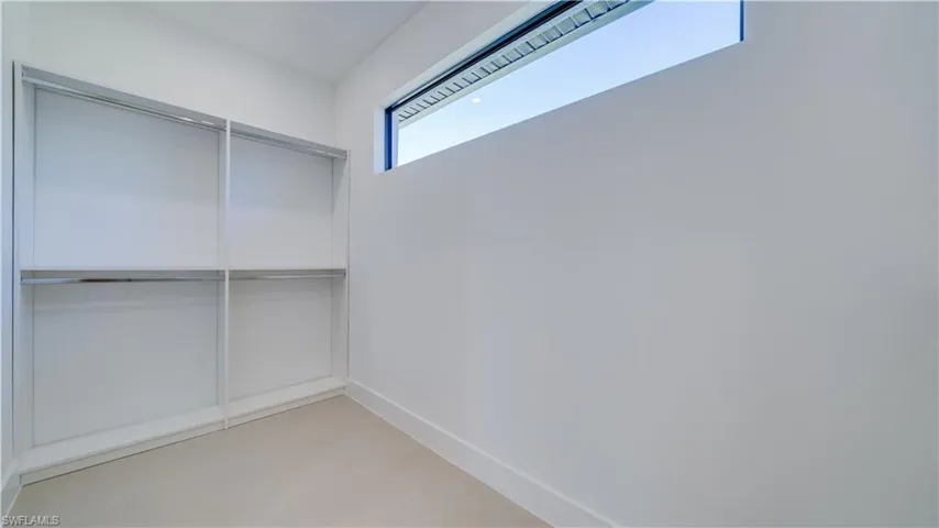 Huge walk-in primary closet with double-sided custom wardrobe system