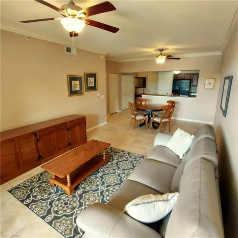 Living area featuring light tile patterned floors, ceiling fan, and crown molding