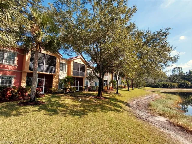 View of front of condo with a sunroom, a balcony, and a back yard