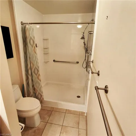 Full bath featuring a shower stall and light tile patterned flooring
