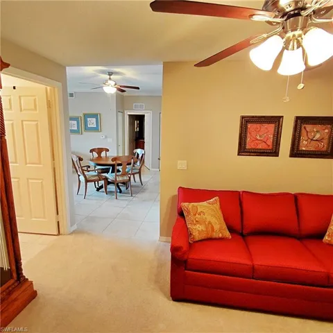 Living area featuring light colored carpet, light tile patterned floors, and ceiling fan