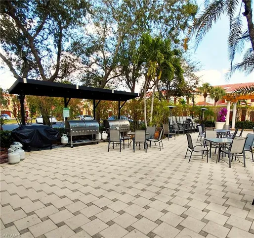 View of community patio with area for grilling, a pergola, and outdoor dining space