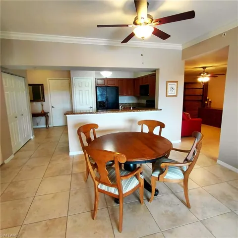 Dining area featuring ornamental molding, light tile patterned flooring, and ceiling fan