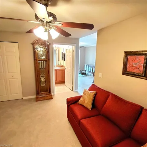Living area featuring light carpet and a ceiling fan