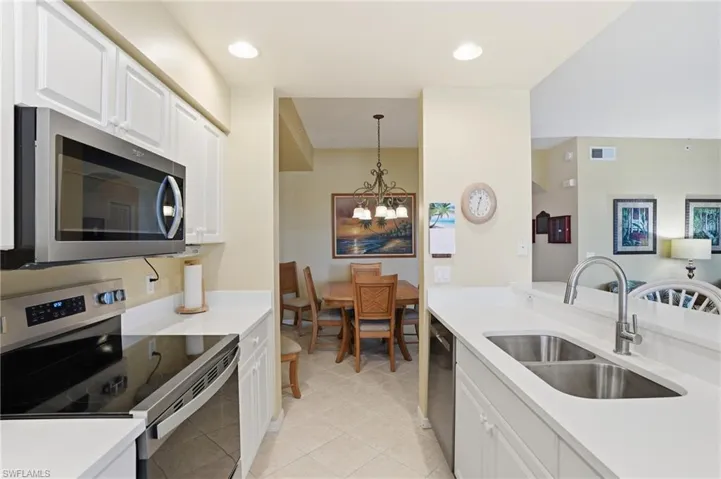 The kitchen features white cabinetry, stainless steel appliances including a microwave and range, and a double basin sink