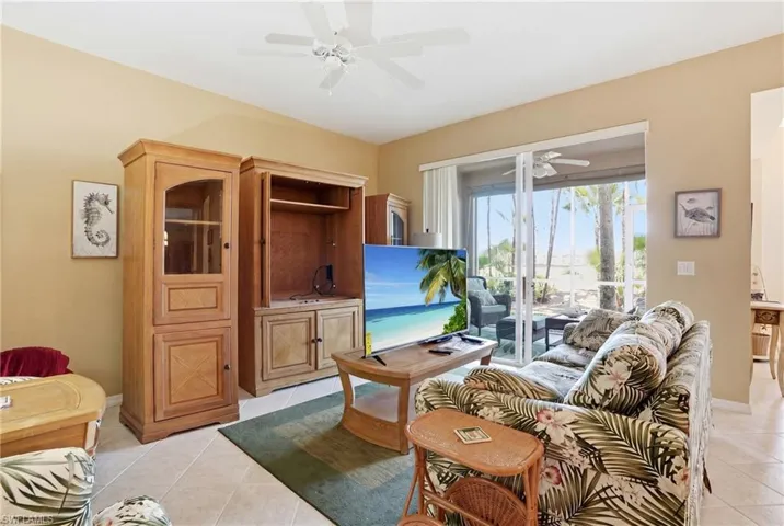 Living area with tiled flooring, a ceiling fan, and sliding glass doors leading to an outdoor space
