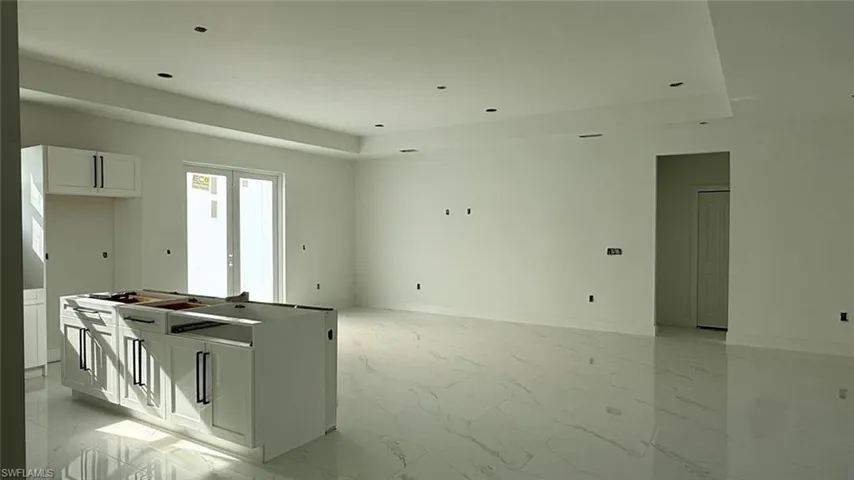 Kitchen featuring marble finish floor, white cabinets, a center island, and open floor plan
