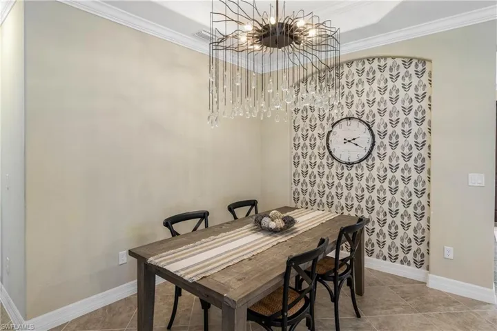 Dining space with suspended lighting, ornamental molding, and light tile patterned floors