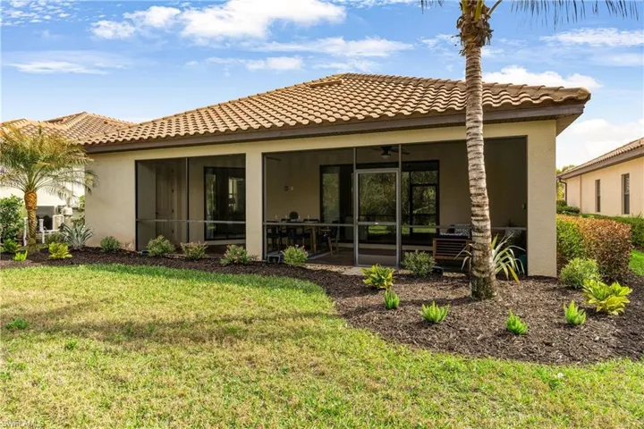 Rear view of property with stucco siding, a tiled roof, a lawn, and a sunroom
