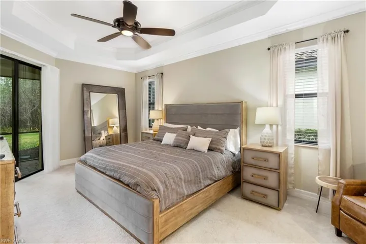 Bedroom featuring access to exterior, light colored carpet, crown molding, a tray ceiling, and a ceiling fan