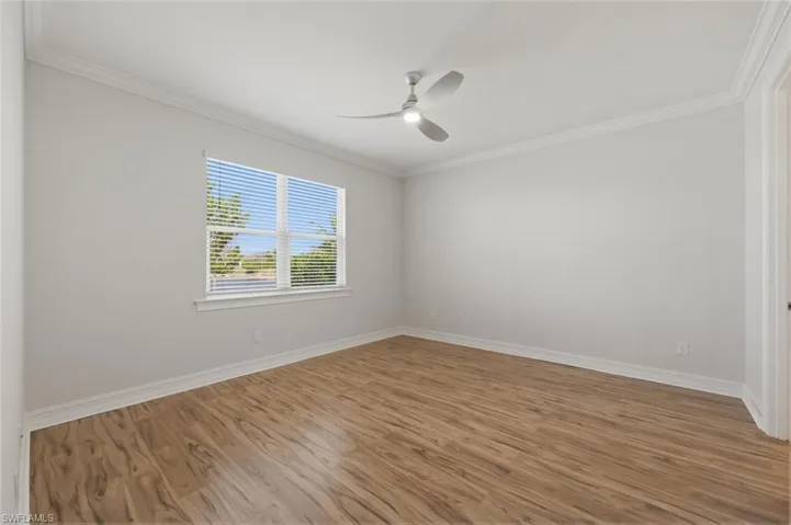 Unfurnished room featuring ornamental molding, light wood-style flooring, and ceiling fan