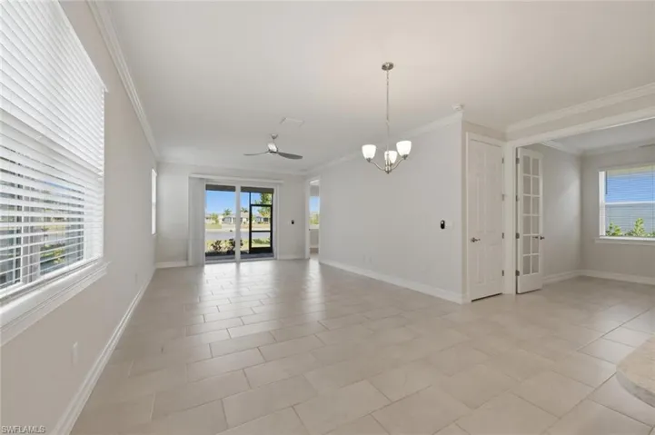 Unfurnished room with ornamental molding, ceiling fan, suspended lighting, and light tile patterned floors