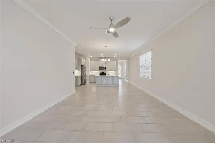 Unfurnished living room featuring a chandelier, ceiling fan, and crown molding