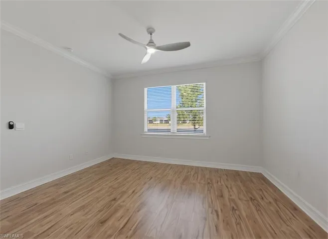 Empty room with light wood-type flooring, crown molding, and a ceiling fan