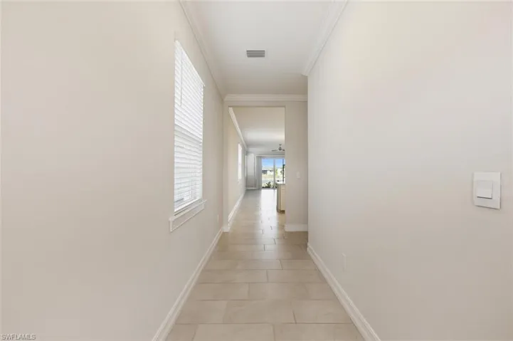 Hallway featuring crown molding and light tile patterned flooring
