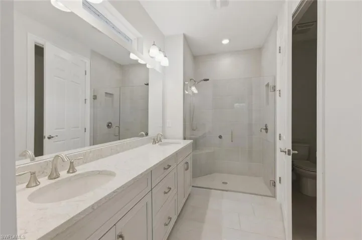 Full bathroom featuring double vanity, a shower stall, light tile patterned floors, and recessed lighting