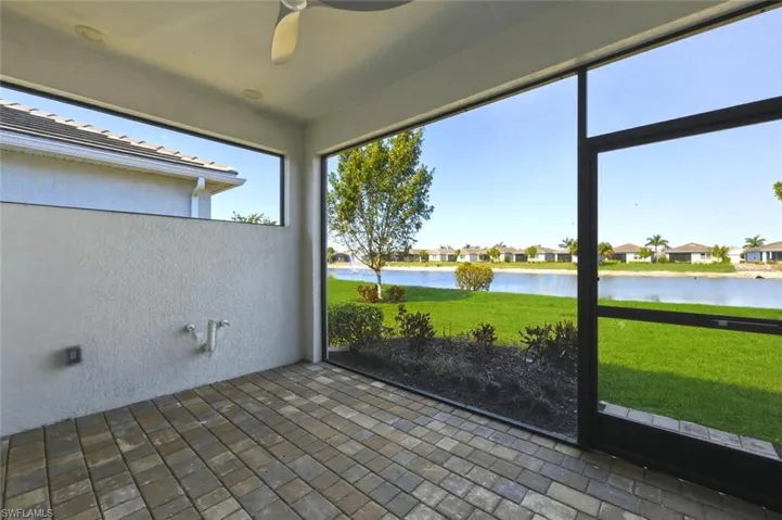Unfurnished sunroom featuring a ceiling fan, a water view, and a patio area