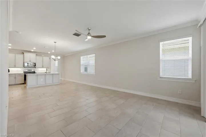 Unfurnished living room featuring a chandelier, a ceiling fan, and ornamental molding