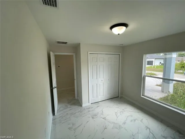 Unfurnished bedroom featuring light marble finish floors, baseboards, and a closet
