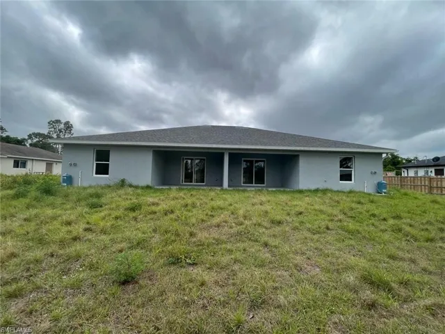 Rear view of property with stucco siding and fence