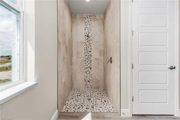 Bathroom featuring a healthy amount of sunlight, tiled shower, and tile floors