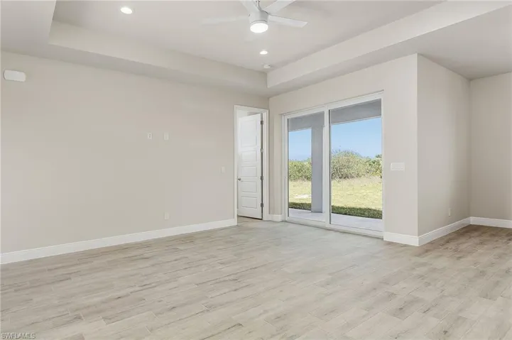 Unfurnished room with a raised ceiling, ceiling fan, and light wood-type flooring