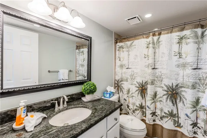 Bathroom featuring toilet, vanity, curtained shower, visible vents, and recessed lighting