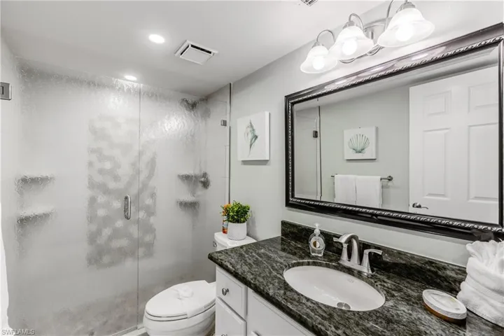 Bathroom with a stall shower, recessed lighting, toilet, visible vents, and vanity