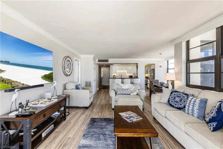 Living area with crown molding, visible vents, and wood finished floors
