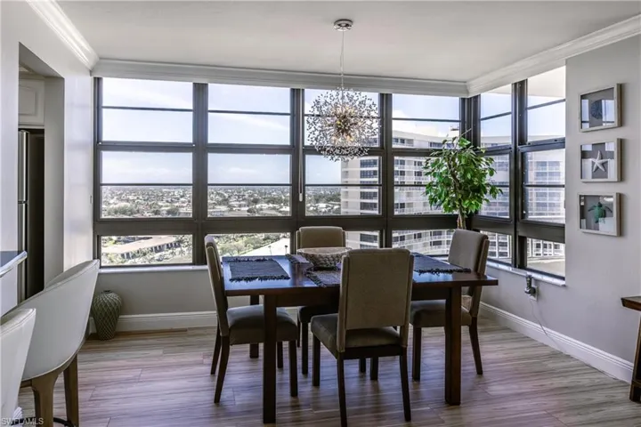 Dining area with baseboards, a notable chandelier, crown molding, and wood finished floors