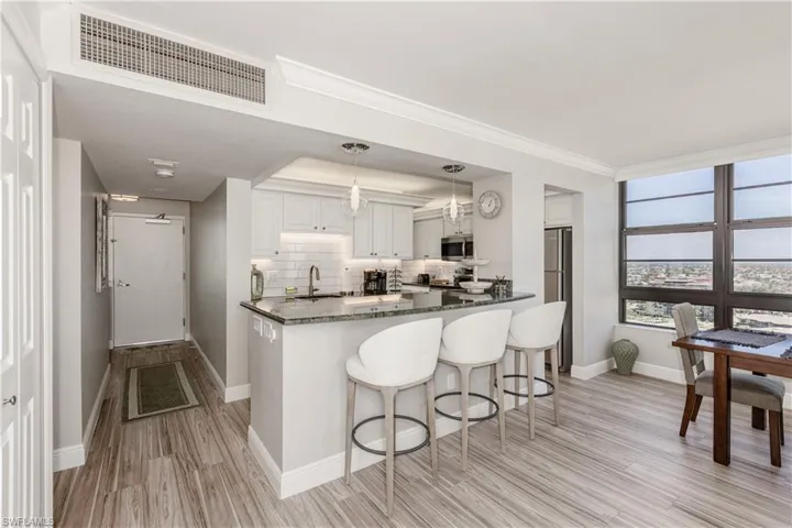 Kitchen with baseboards, appliances with stainless steel finishes, a kitchen breakfast bar, and visible vents