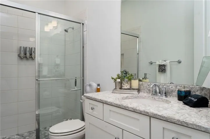 Bathroom featuring a shower with glass enclosure, white square wall tiles, and pebble floor