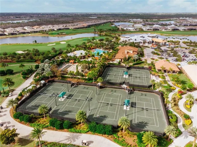Four hard tennis courts with perimeter fencing, surrounded by mature landscaping and palm trees