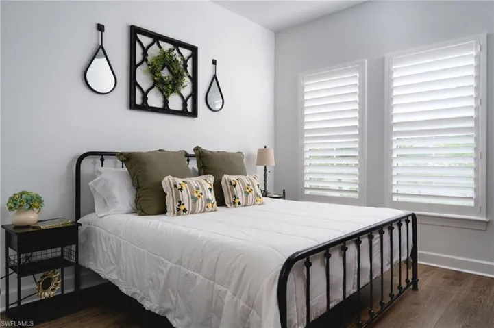 Bright room featuring two windows with white plantation shutters and wood-finish flooring