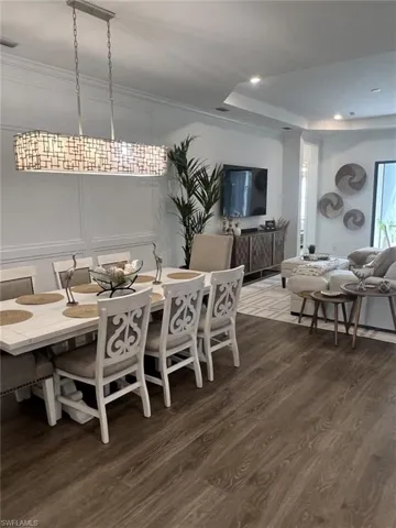 Open-concept interior featuring wood-finish flooring, a decorative linear chandelier, and recessed lighting