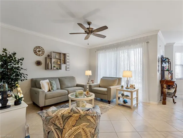 Living area featuring light tile patterned floors, baseboards, ornamental molding, and ceiling fan