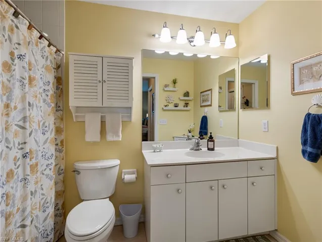 Full bath with toilet, a shower with shower curtain, and vanity